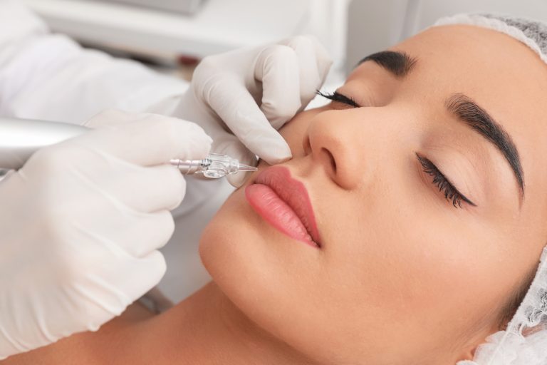 Young woman undergoing procedure of permanent lip makeup in tattoo salon, closeup